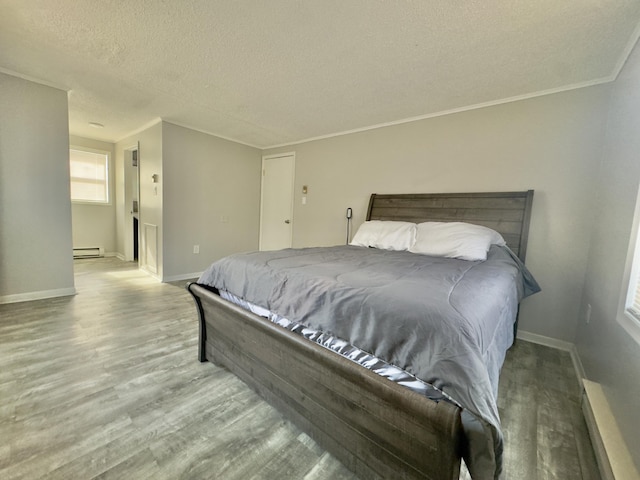 bedroom with baseboards, baseboard heating, wood finished floors, and a textured ceiling