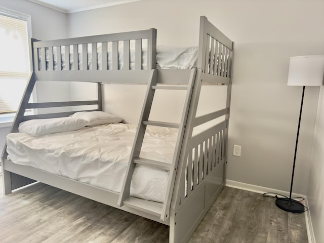 bedroom with multiple windows, baseboards, and wood finished floors