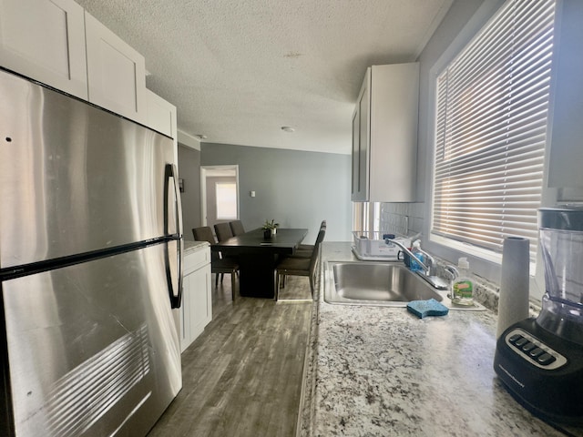 kitchen with white cabinets, dark wood-style floors, freestanding refrigerator, and a sink