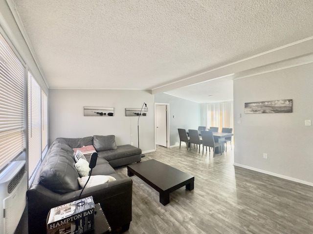 living area with vaulted ceiling, wood finished floors, baseboards, and a textured ceiling