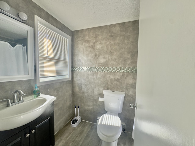 bathroom with vanity, tile walls, toilet, and a textured ceiling