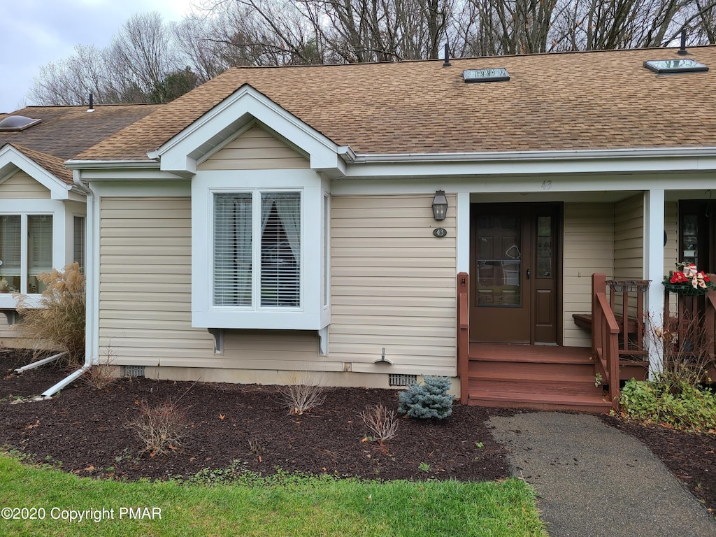 view of front of home featuring crawl space, covered porch, and a shingled roof