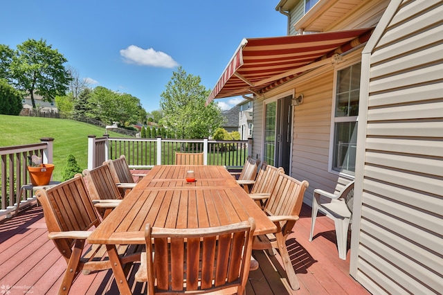 deck featuring outdoor dining area and a lawn