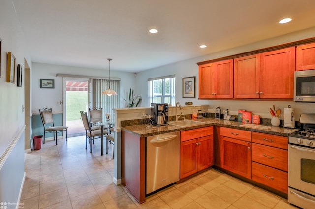 kitchen with a sink, appliances with stainless steel finishes, a peninsula, brown cabinetry, and recessed lighting
