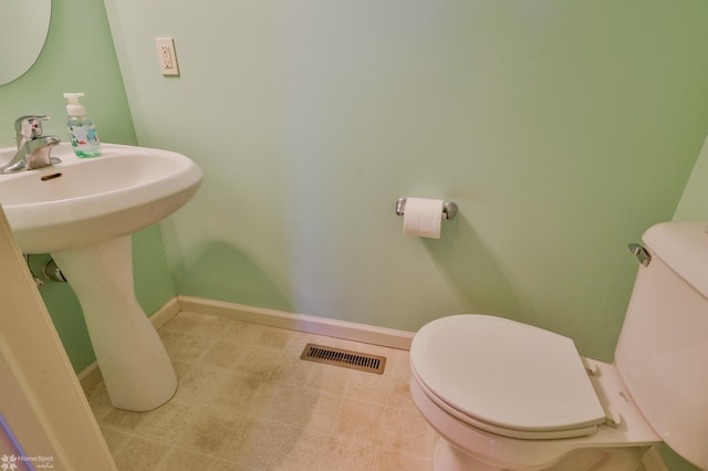 bathroom with toilet, baseboards, and a sink
