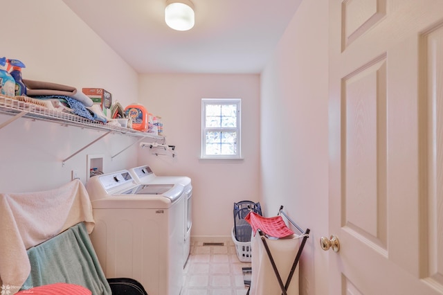 clothes washing area with washer and dryer, light flooring, and baseboards
