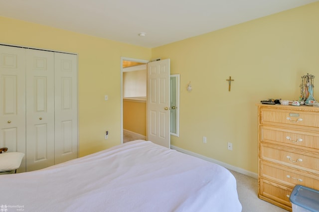 bedroom with a closet, light carpet, and baseboards