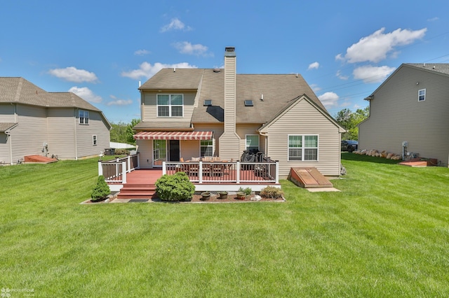 rear view of property with a deck, a chimney, and a lawn