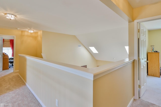 hall featuring an upstairs landing, carpet floors, baseboards, and lofted ceiling