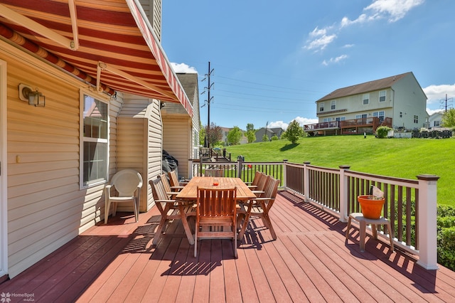 wooden deck featuring outdoor dining space and a lawn