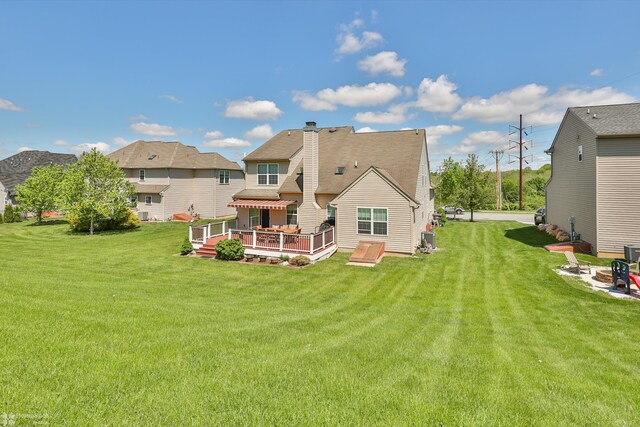 back of property featuring a deck, a lawn, central air condition unit, and a chimney
