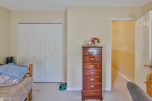 bedroom featuring light colored carpet, a closet, and baseboards