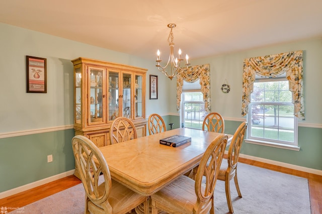 dining area featuring a chandelier, wood finished floors, and baseboards