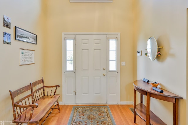 foyer featuring light wood-type flooring, baseboards, and a high ceiling