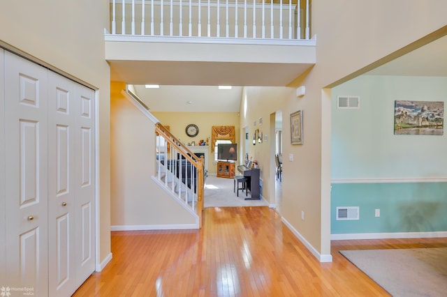 entrance foyer with hardwood / wood-style flooring, a towering ceiling, stairs, and baseboards