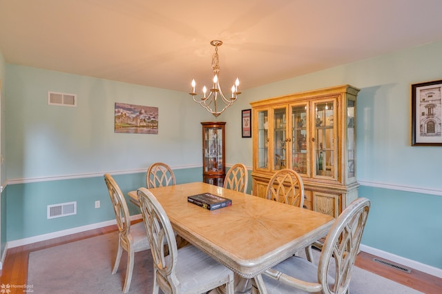 dining room with a chandelier, baseboards, and wood finished floors