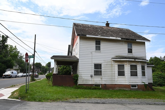 595 N Courtland St, East Stroudsburg, PA 18301 - view of side of property with a chimney, a shingled roof, and a yard