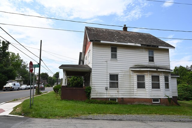 595 N Courtland St, East Stroudsburg, PA 18301 - view of side of property with a chimney, a shingled roof, and a yard