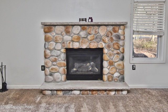 interior details featuring a stone fireplace, carpet flooring, and baseboards