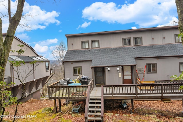 back of house featuring a shingled roof and a wooden deck