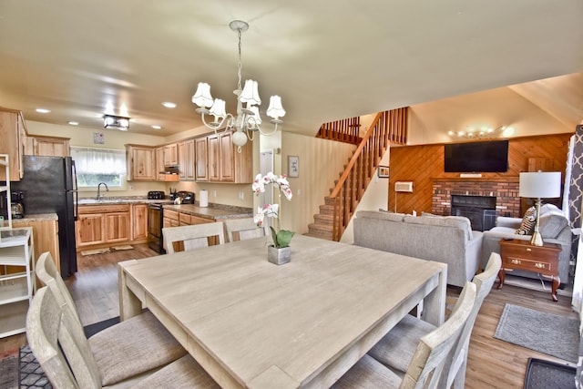 594 Sullivan Trl, Long Pond, PA 18334 - dining room featuring a chandelier, stairs, light wood-style floors, a brick fireplace, and wood walls