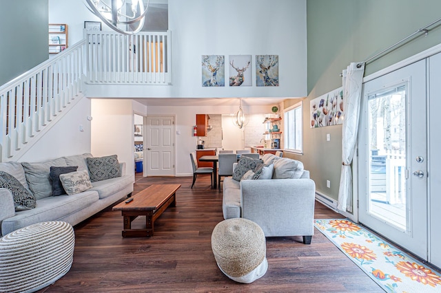 living room featuring a baseboard radiator, wood finished floors, stairs, a high ceiling, and a notable chandelier