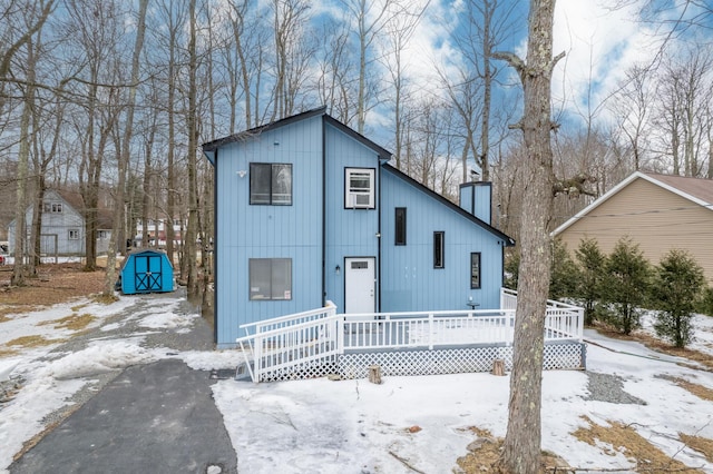 view of front of property with an outbuilding, covered porch, a chimney, and a storage shed