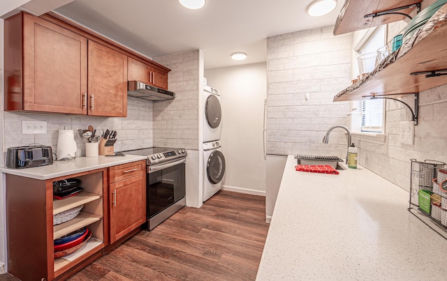 kitchen with brown cabinets, stainless steel electric range oven, under cabinet range hood, and stacked washing maching and dryer