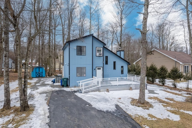 view of front facade featuring a storage shed, a chimney, and an outdoor structure