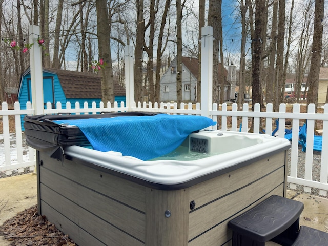 view of patio with a hot tub, fence, and an outdoor structure