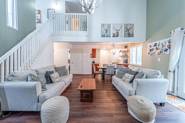 living area with dark wood-style floors, stairs, a high ceiling, and a notable chandelier