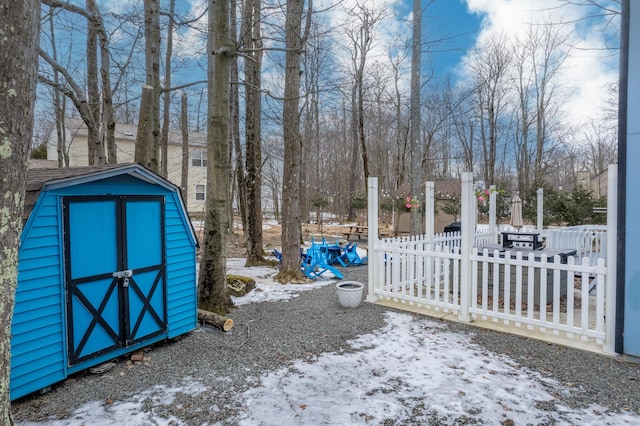 snowy yard with an outbuilding, fence, and a shed