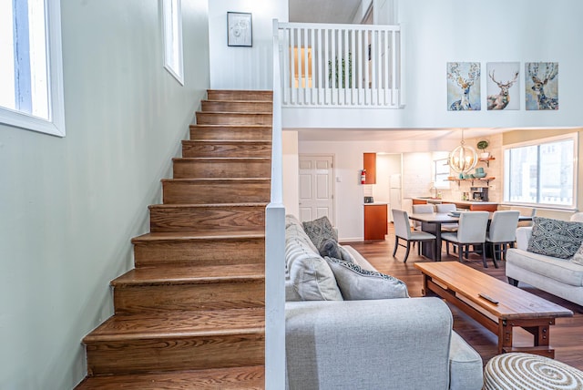 stairs featuring a chandelier, a high ceiling, and wood finished floors