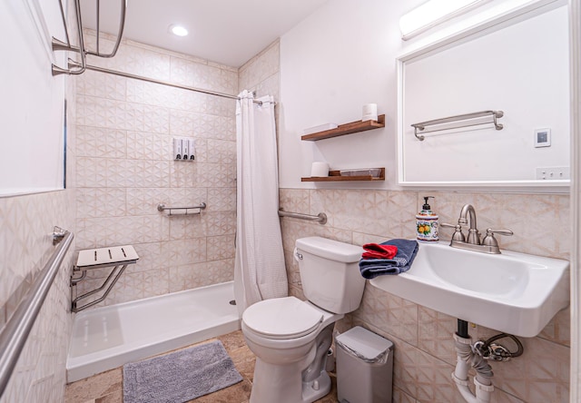 bathroom featuring tile walls, toilet, wainscoting, a sink, and a shower stall