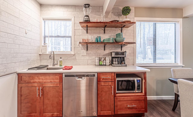 kitchen with appliances with stainless steel finishes, dark wood-style flooring, a sink, light countertops, and backsplash