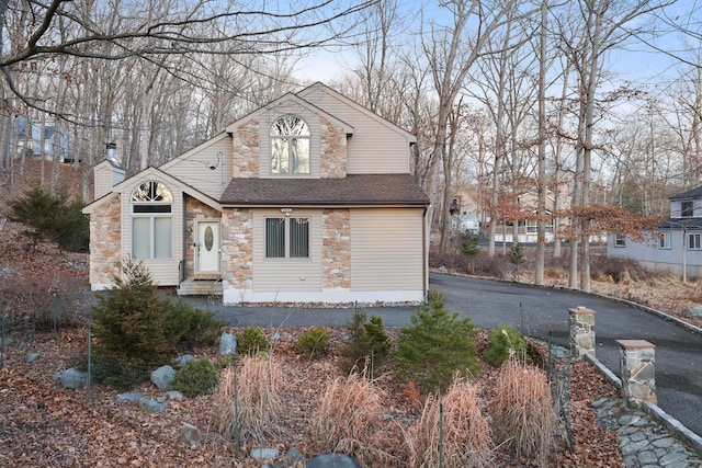 view of front of property with driveway, a chimney, entry steps, and roof with shingles