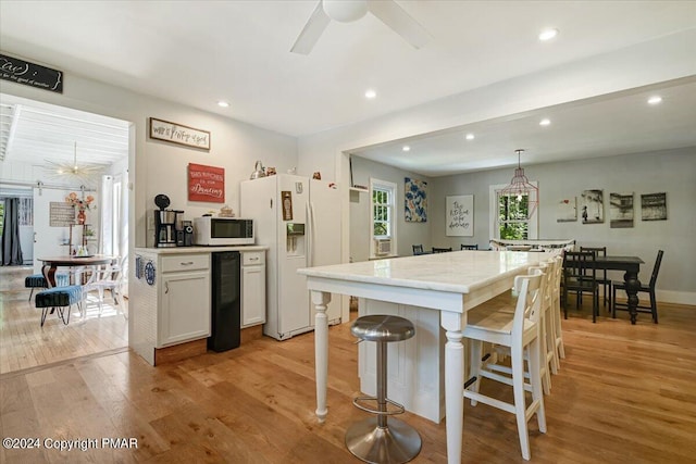188 Olde Schoolhouse Rd, Cresco, PA 18326 - kitchen with white appliances, a ceiling fan, a kitchen island, light wood-style flooring, and a kitchen bar
