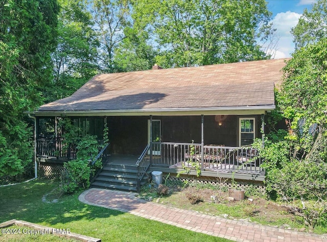 view of front of house with a chimney, roof with shingles, covered porch, and a front lawn