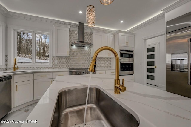 kitchen with tasteful backsplash, appliances with stainless steel finishes, white cabinets, a sink, and wall chimney exhaust hood