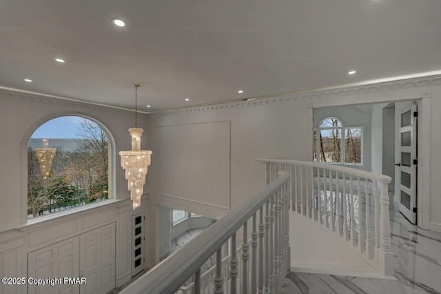 hall with marble finish floor, a wealth of natural light, an upstairs landing, and an inviting chandelier