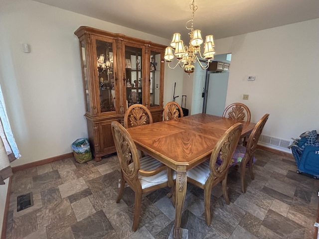 dining room with baseboards, stone finish flooring, and a notable chandelier
