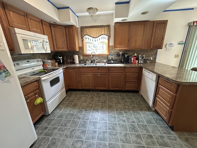 kitchen featuring a sink, white appliances, brown cabinetry, a peninsula, and decorative backsplash