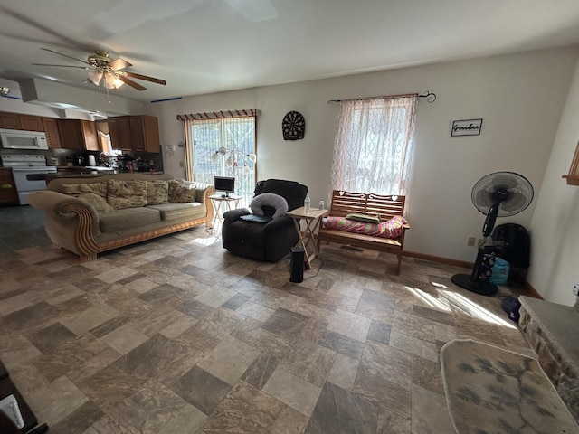 living area featuring stone finish floor, baseboards, and a ceiling fan