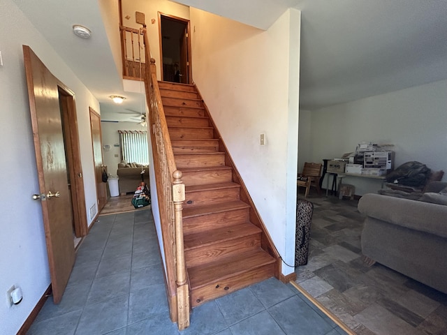 staircase with ceiling fan and tile patterned floors