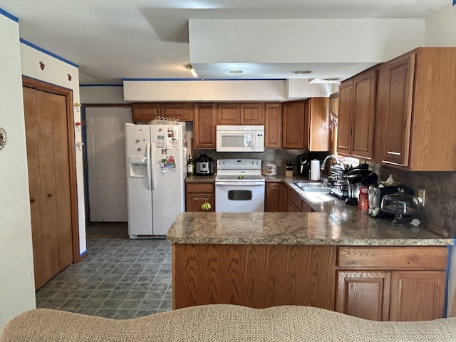 kitchen featuring brown cabinets, a sink, white appliances, a peninsula, and tasteful backsplash