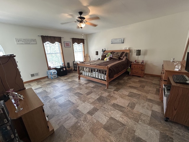 bedroom featuring baseboards, a ceiling fan, stone finish flooring, and visible vents