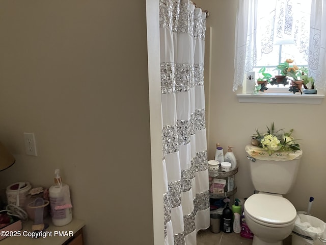 bathroom with a shower with curtain, toilet, and tile patterned floors