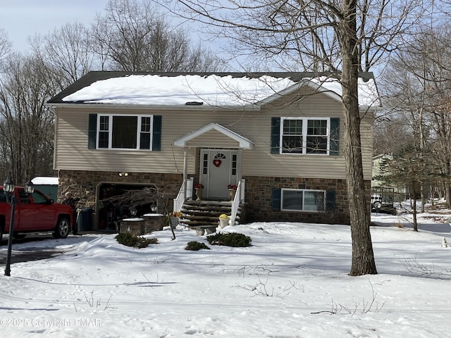 bi-level home featuring stone siding and an attached garage