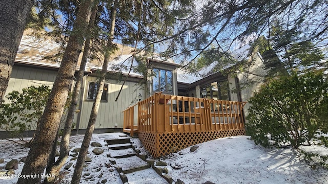 snow covered back of property featuring a wooden deck