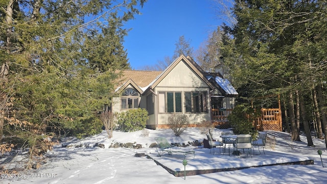 snow covered back of property with a deck and stucco siding